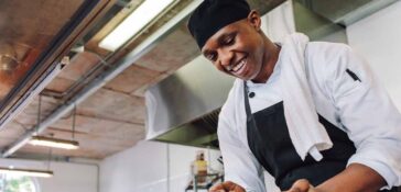 Chef at restaurant spooning vegetables